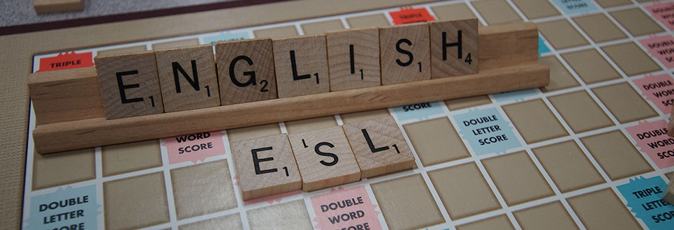Scrabble board with "ENGLISH" and "ESL" laid out with the letter pieces.